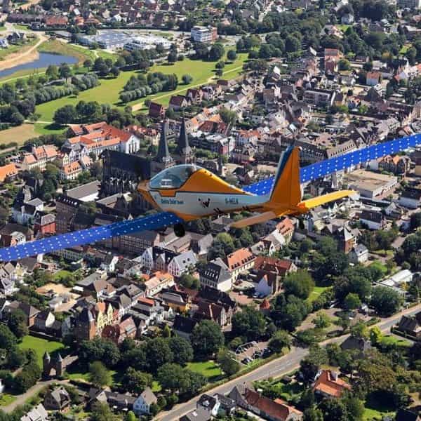 Elektra Solar plane in flight over town