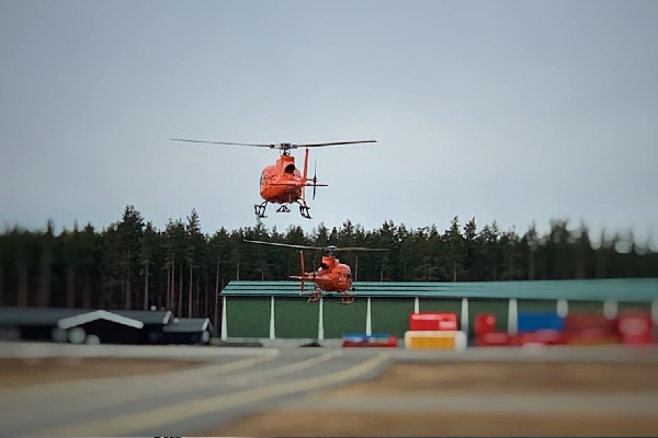 Ostnes Helicopters Gallery. Orange helicopters in the hover