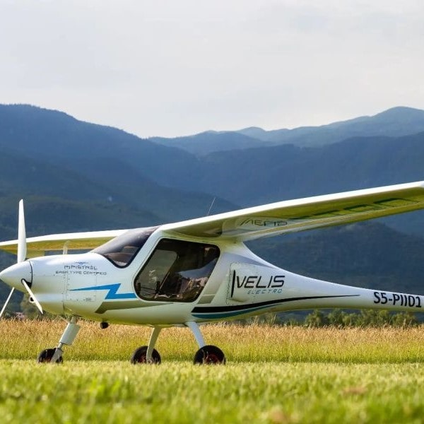 Pipistrel Aircraft grounded in field with mountains