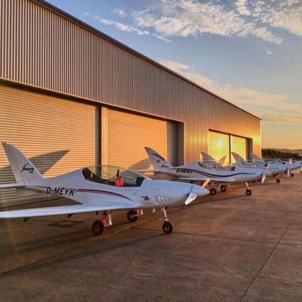 Shark aeroplanes lined up outside hanger at sunset